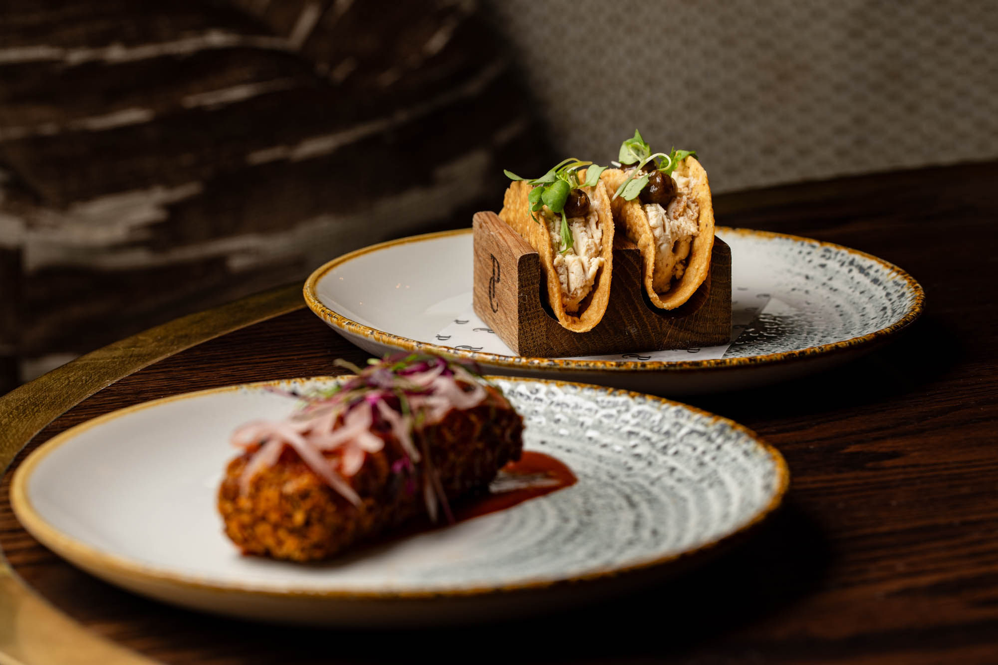 two dishes on the grey plates served on the brown table at Pearly Cow