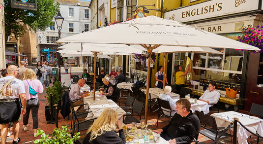 exterior shot of terrace at English's of Brighton populated with people enjoying their food and drinks. No.9 among Brighton's Best Restaurants at the BRAVO Awards 2026. Located close to Riddle and Finns