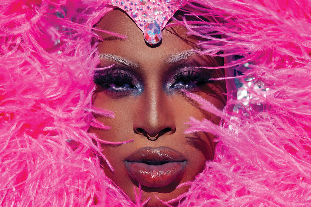 A person's face behind pink feathers. At The Helm Gallery for Brighton Pride in 2024