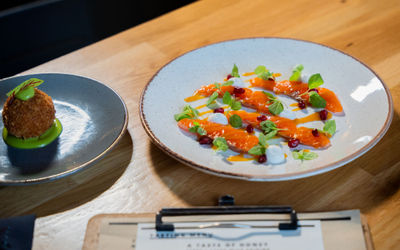 A white plate with delicate garnishes on top of a sliced salmon dish.
