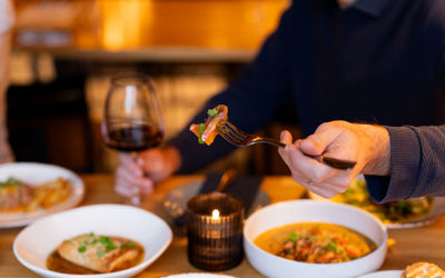 A man's hands holding a glass of wine and eating some food.