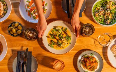 Overhead photo of plates of food laid out on a table and a pair of hands placing one of the plates down.