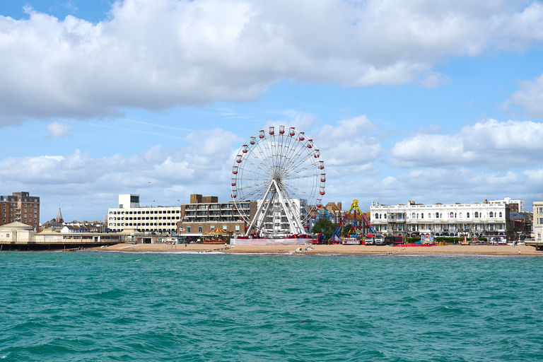 A view from the pier of the coast line of Worthing's town with the fairground and ferris wheel on the beach. Lots of places for Sussex pub walks nearby.