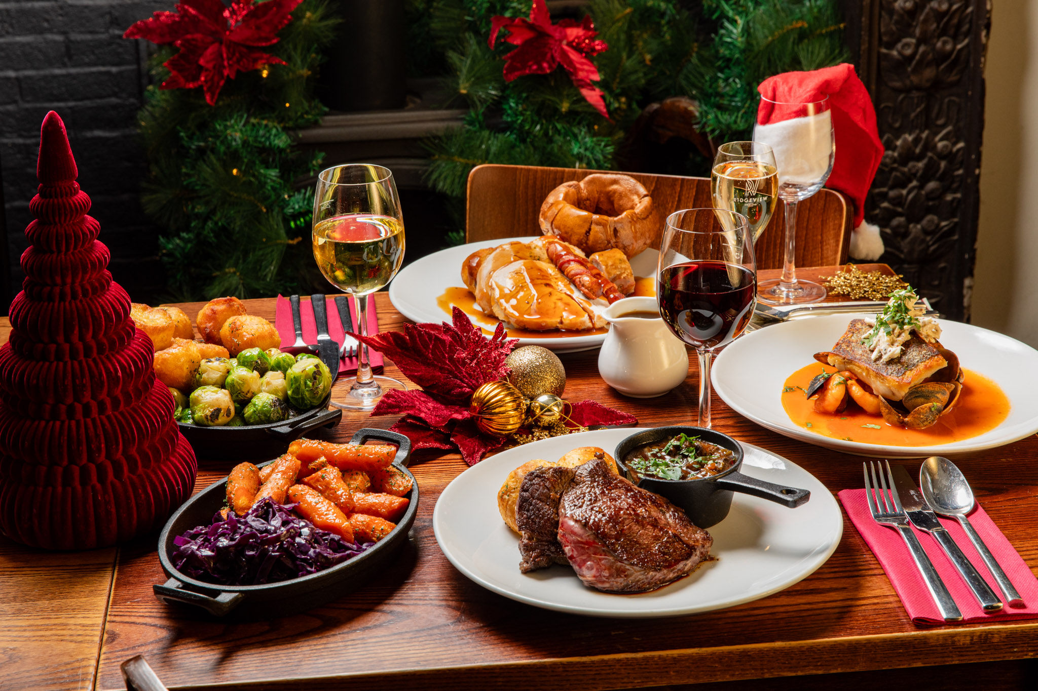 A table of food with Christmas food laid out and glasses of wine.