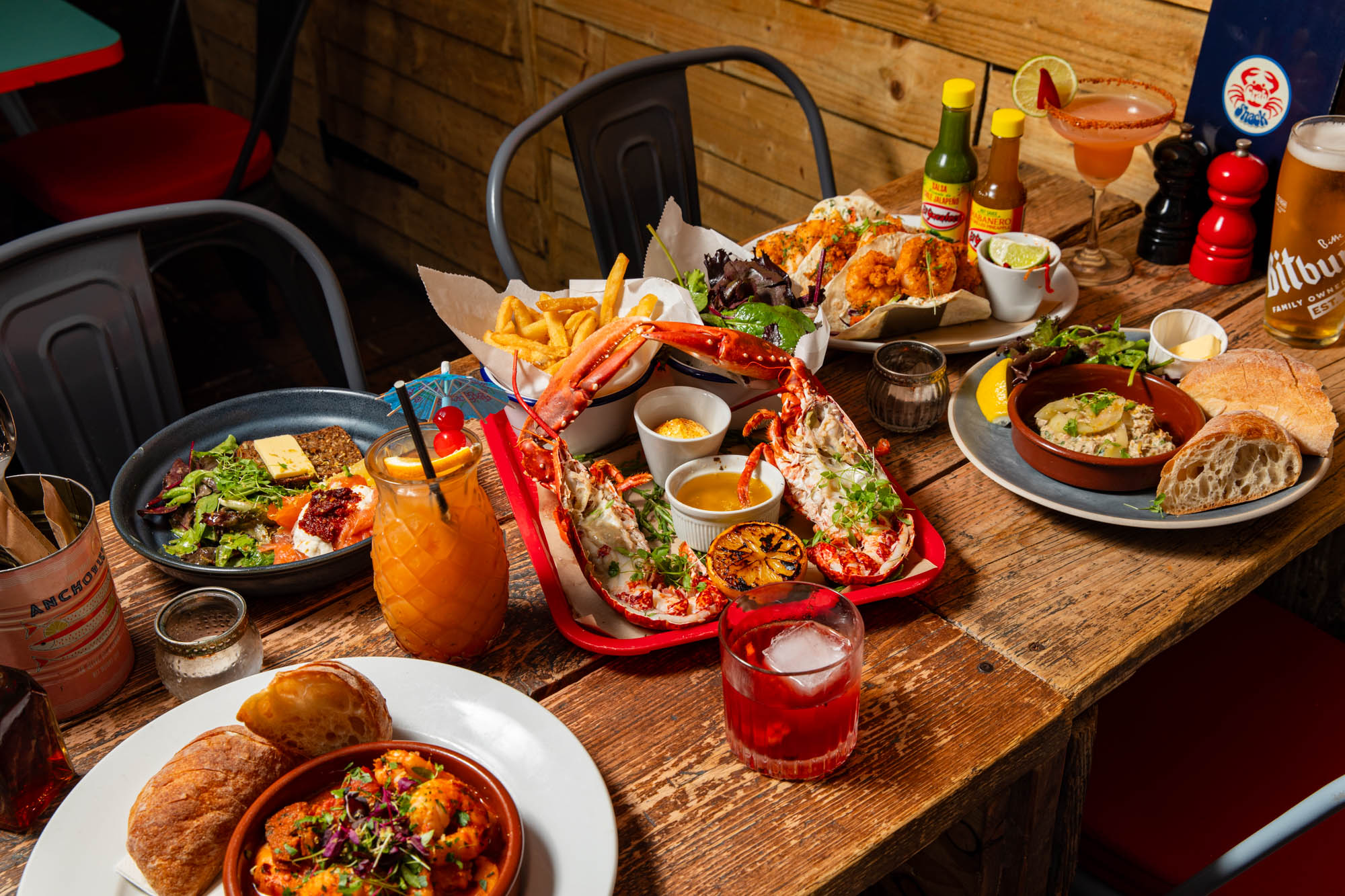 side shot of of the wooden table laid out with seafood dishes from Crabshack