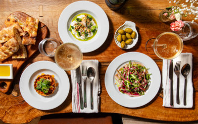 over head shot of the table laid out with three Italian dishes and glasses of wine