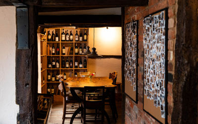 interior shot of the corner of Poco, wooden furniture walls and shelves with wines at Poco Alfriston