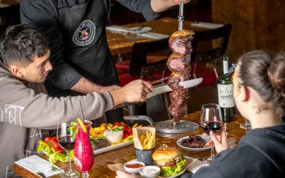a man cutting of the meat of the stick at Fogo de Chão Brazilian Steakhouse