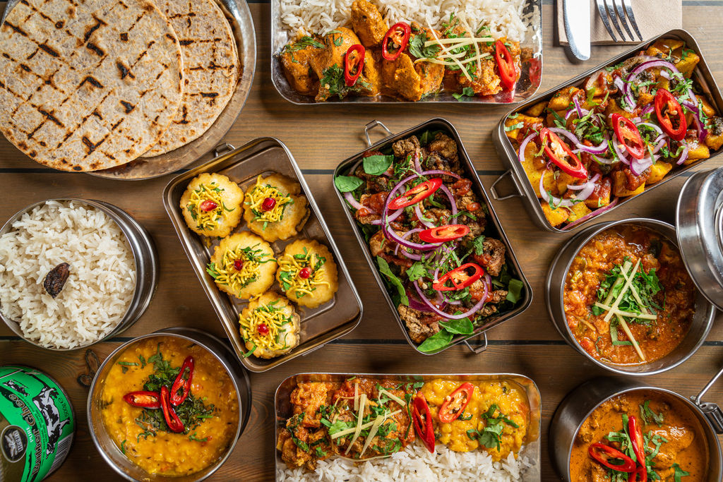 Mowgli Street Food Brighton, Indian food served in tiffins laid out on a wooden table.
