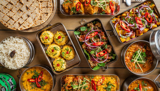 Mowgli Street Food Brighton, Indian food served in tiffins laid out on a wooden table.