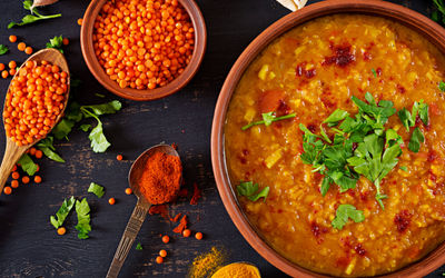 Pavel Indian Restaurant in Brighton colourful orange lentils, a wooden spoon and an orange coloured souther indian dish at Pavel restaurant. Part of our Indian restaurant Brighton guide.