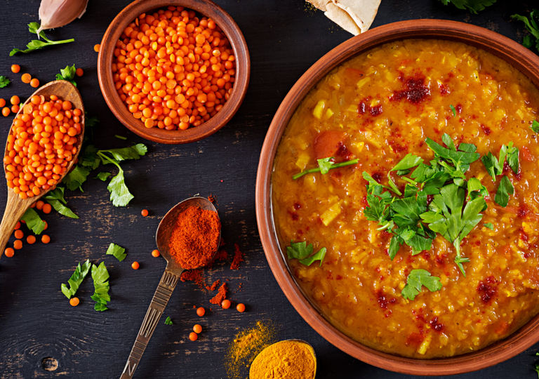 colourful orange lentils, a wooden spoon and an orange coloured souther indian dish at Pavel restaurant. Part of our Indian restaurant Brighton guide.