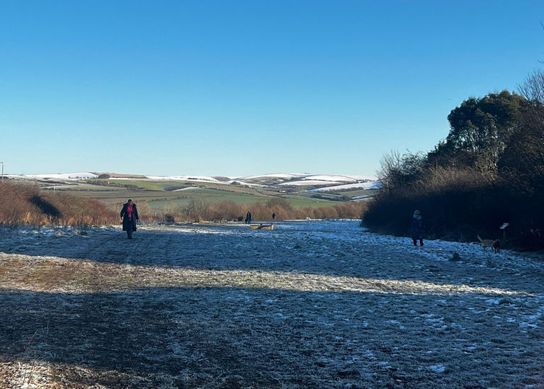 A snowy winter walk in Sussex with snow topped hills in the distance and a crisp bright blue sky.
