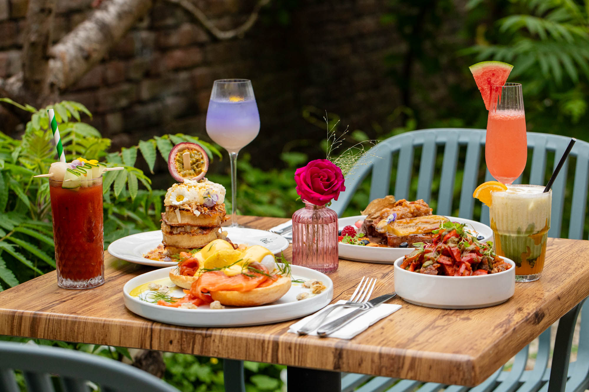 exterior shot of the garden table at Oeuf Brighton, table laid out with various brunch dishes and couple of drinks