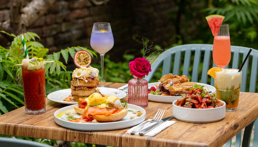 exterior shot of the garden table at Oeuf Brighton, table laid out with various brunch dishes and couple of drinks