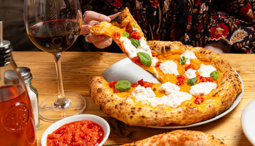 Vegan pizza with fresh basil and a glass of red wine.