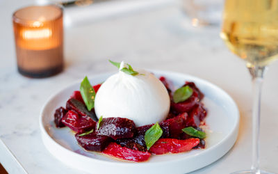 burrata served with beetroots and paprika on the white plate paired with white wine