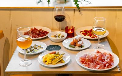 side shot shot of the square white table at Curio, laid out with 7 small plates and drinks.