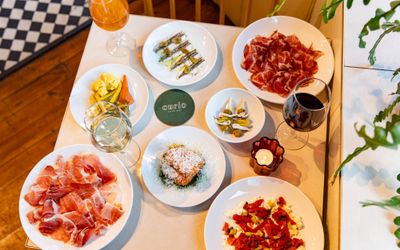 over head shot of the square white table at Curio, laid out with 7 small plates and drinks.