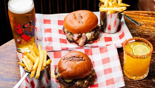 two incredible looking burgers with fries and drinks at the Fountain Head Pub. Boysterous Burgers are new to the Brighton pub scene. On a chequered red and white table cloth. Best burgers in Brighton