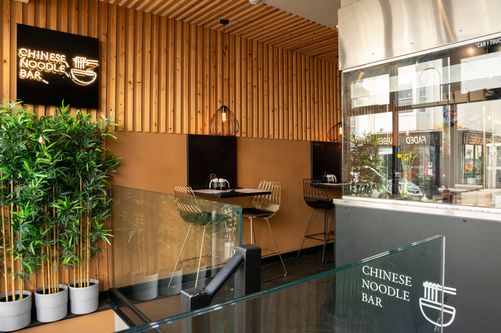 interior shot of the Shaanxi restaurant, wooden walls, baro stools and tables, green plant on the wall as a decoration