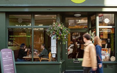 exterior shot of the terre a terre, olive green exterior, with people passing by. This vegetarian pioneer is runner up in this year's Brighton restaurant Awards and finished first place in the 2024 BRAVO Awards.