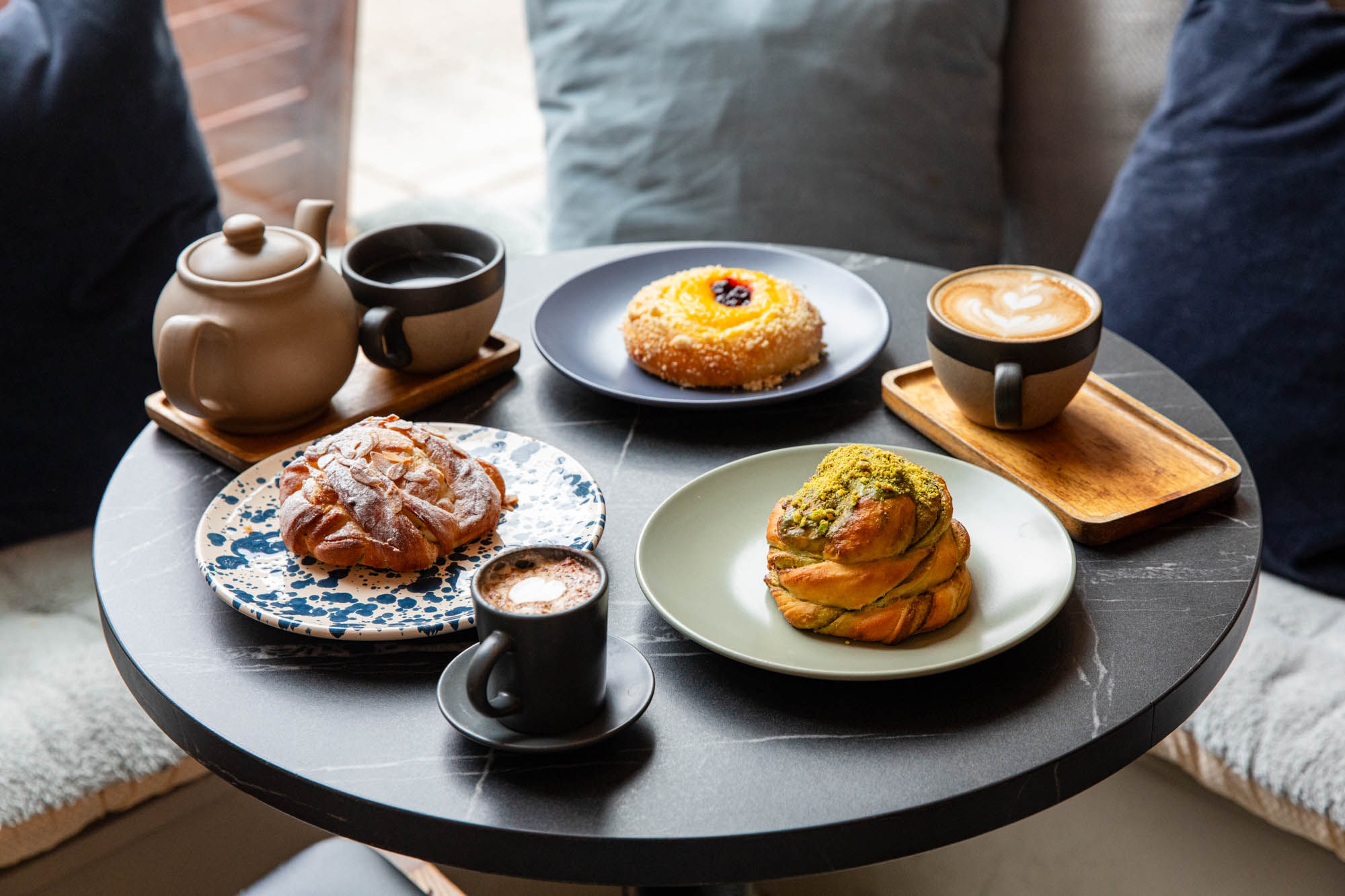 side shot of three pastries served with flat white coffes and tea