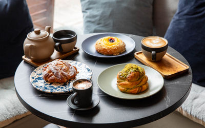 side shot of three pastries served with flat white coffes and tea
