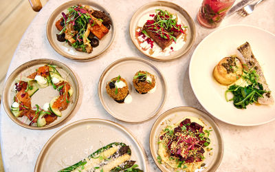 Plates of colourful food laid out on a table with a mocktail.