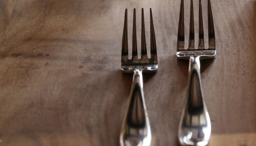 two very shiny forks on a wooden table