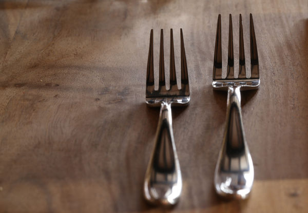 two very shiny forks on a wooden table