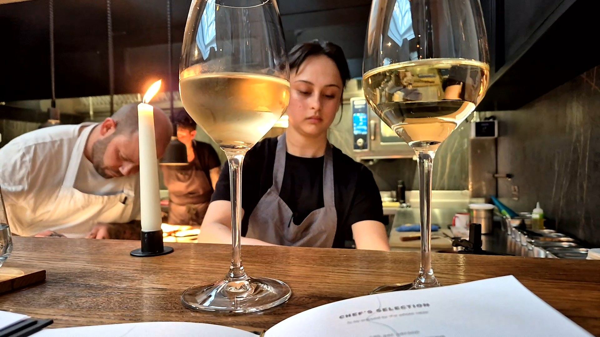 Two glasses of wine at the pass with the chefs in the background.
