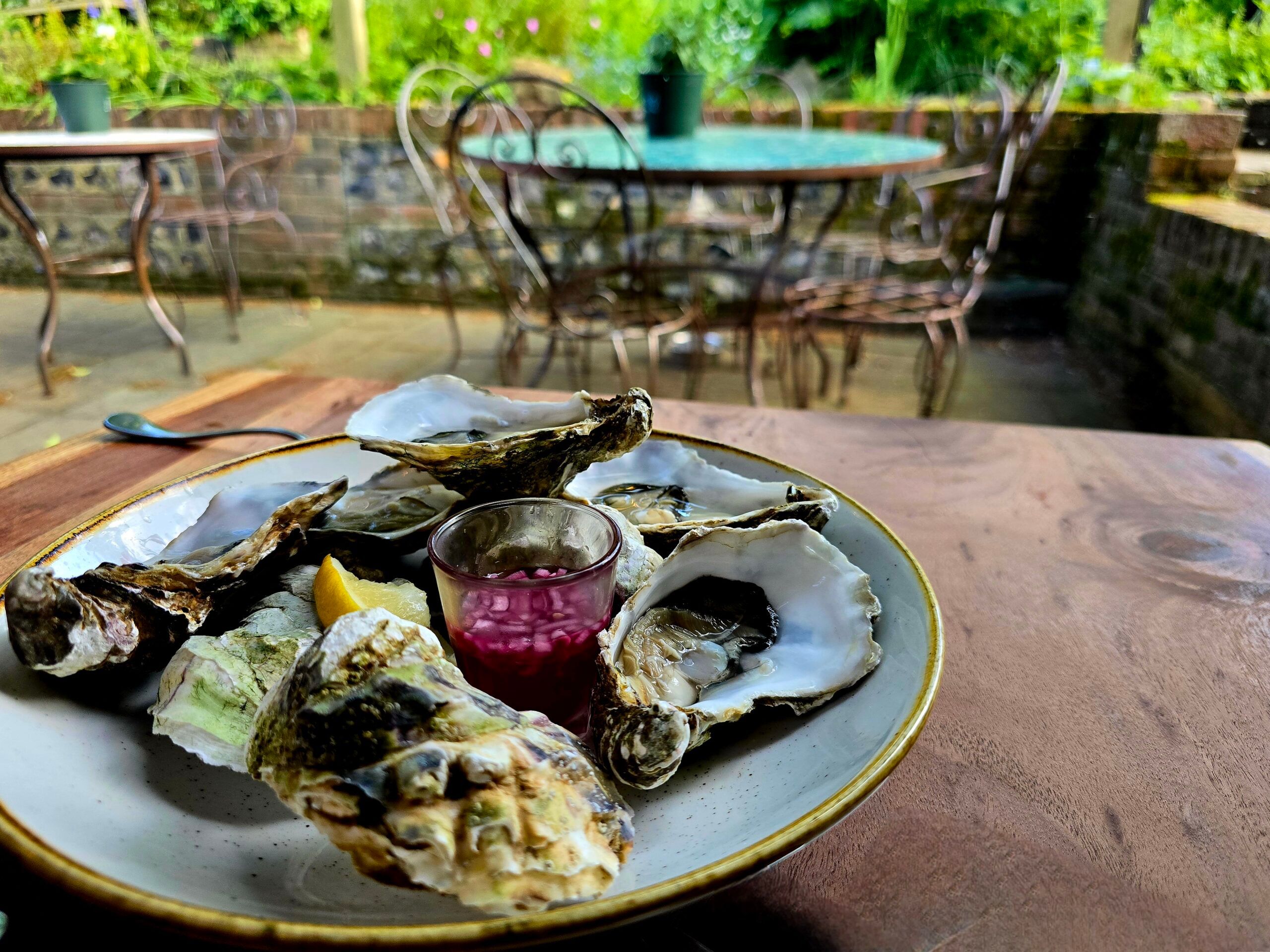 plate with oysters served on the wooden table in the garden of The Jolly Sportman