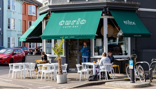 Exterior photo for Curio on a sunny day with the green signeage.