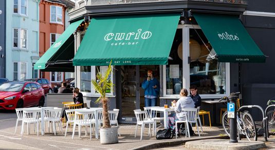 Exterior photo for Curio on a sunny day with the green signeage.