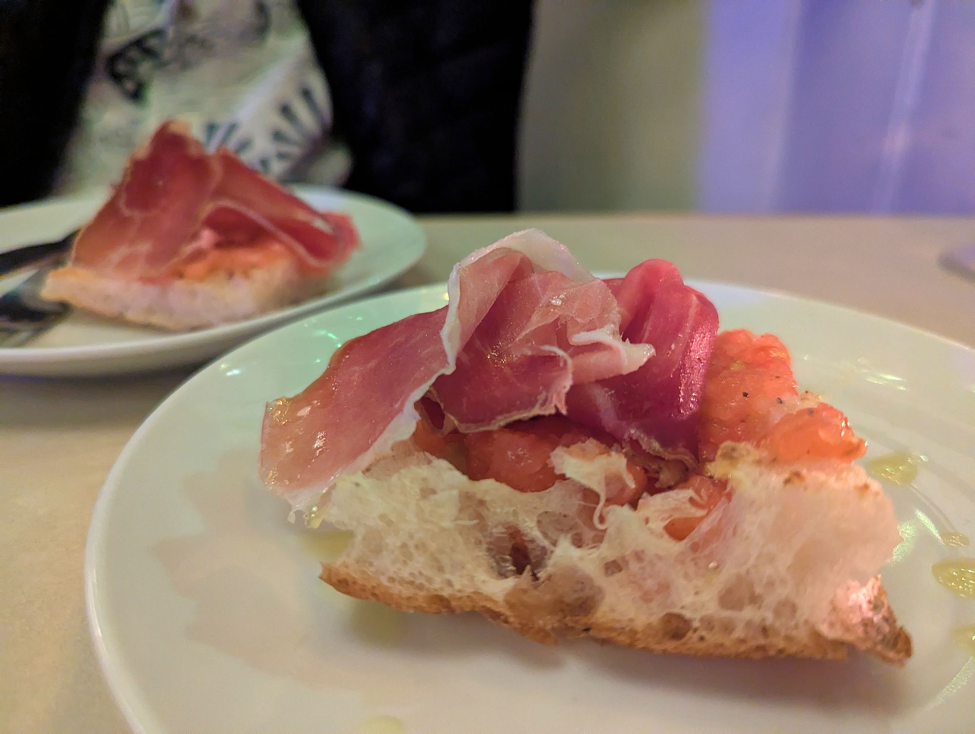 A piece of bread with charcuterie placed on the top.