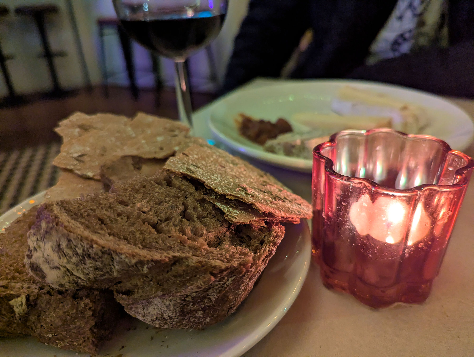 Sliced bread and wine next to a tea light at Curio.