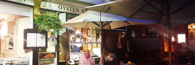 Restaurant lit up at night with people dining alfresco.