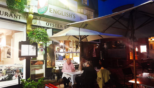 Restaurant lit up at night with people dining alfresco.