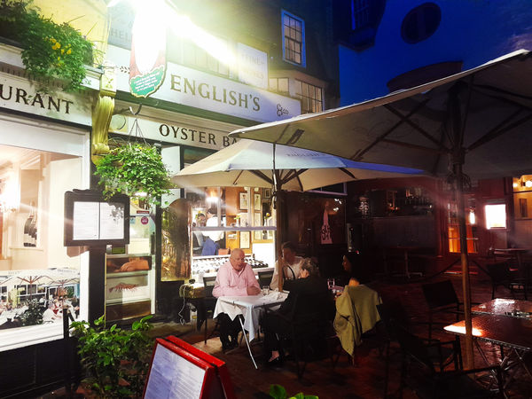 Restaurant lit up at night with people dining alfresco.