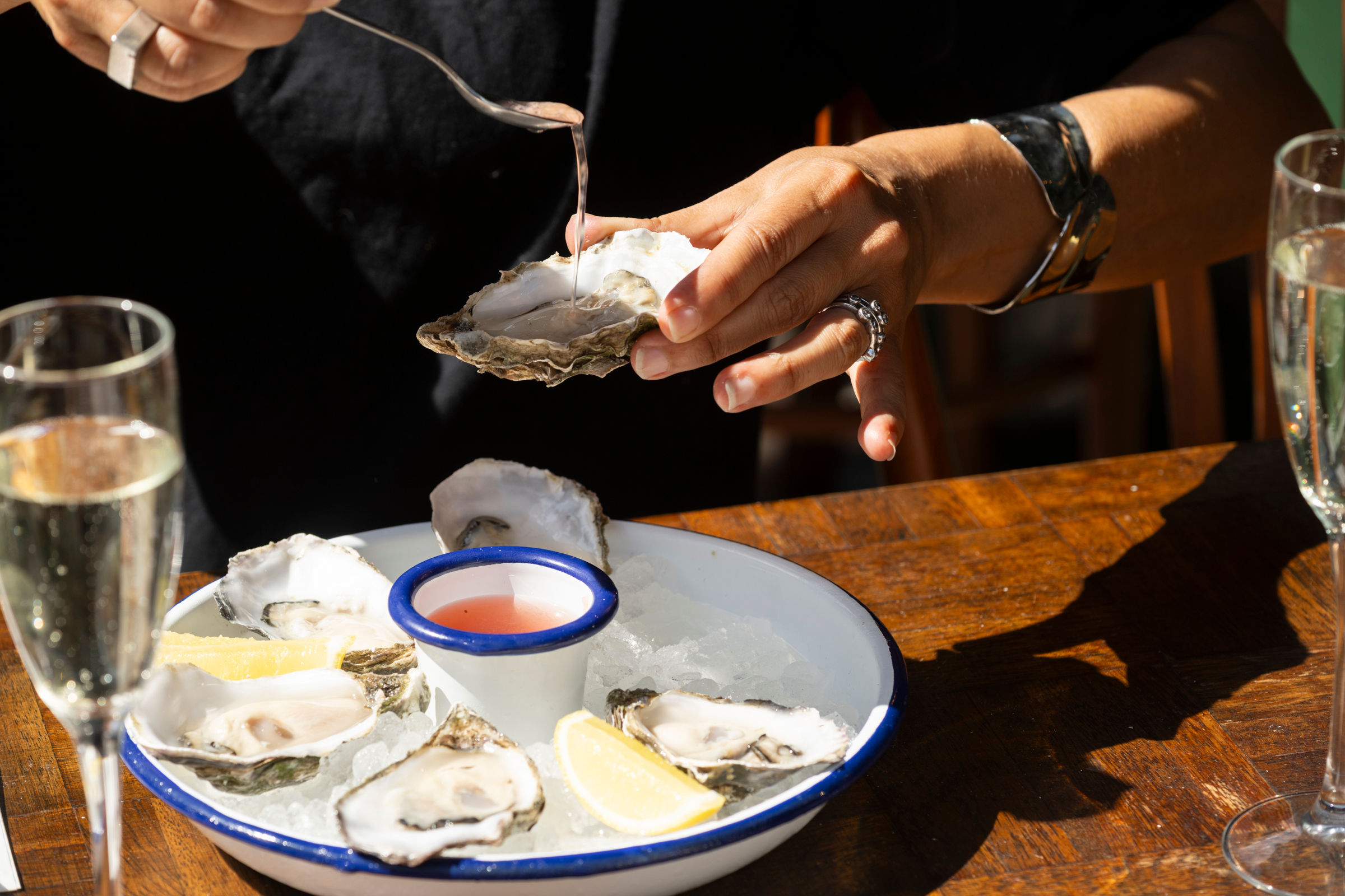 person adding sauce on to oyster 