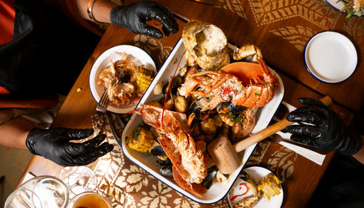An aerial shot of diners in Brighton's Gothic Crab. Sharing lobster together and using black latex gloves. The Gothic Crab is one of Brighton's newest restaurants. Seafood restaurant in Brighton
