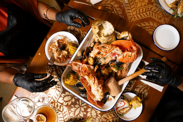 An aerial shot of diners in Brighton's Gothic Crab. Sharing lobster together and using black latex gloves. The Gothic Crab is one of Brighton's newest restaurants.