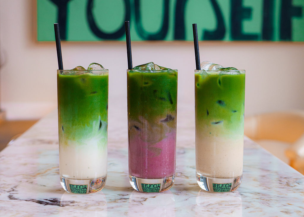 Colourful matcha drinks on a marble surface.