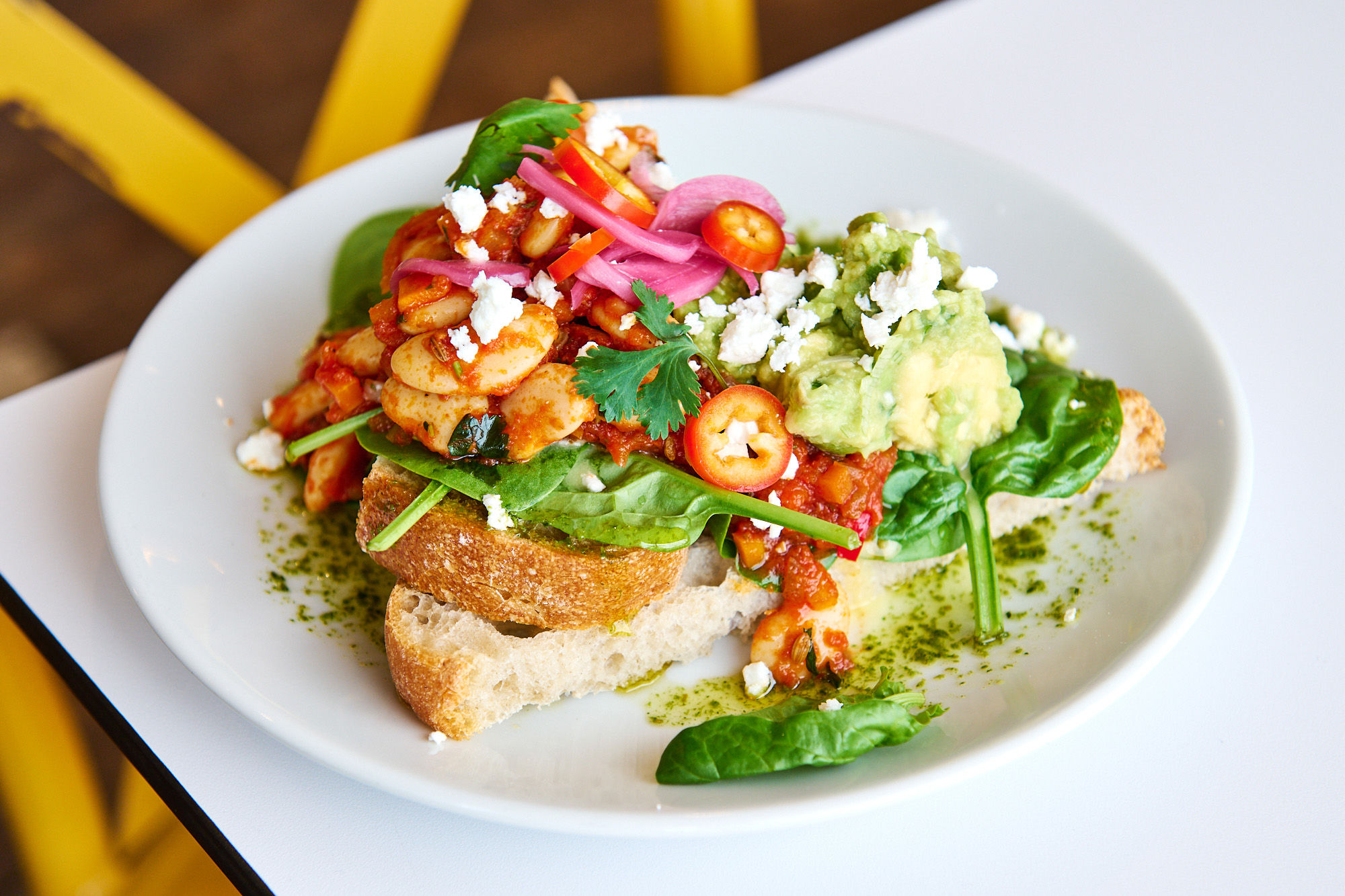 Cowboy Sunrise - smokey baked beans, pink pickled onions, smashed avo, feta, herb oil and coriander on toasted sourdough.