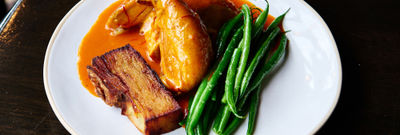 A plate of roast chicken, saffron and tomato butter sauce, French beans.