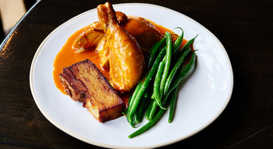 A plate of roast chicken, saffron and tomato butter sauce, French beans.