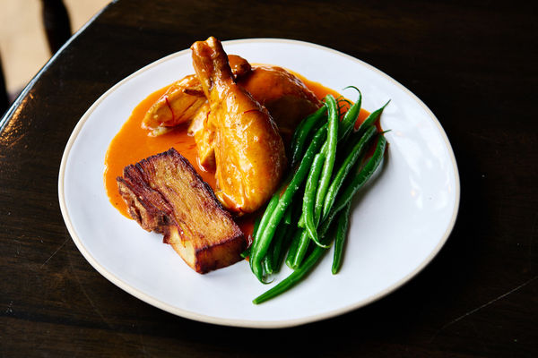 A plate of roast chicken, saffron and tomato butter sauce, French beans.
