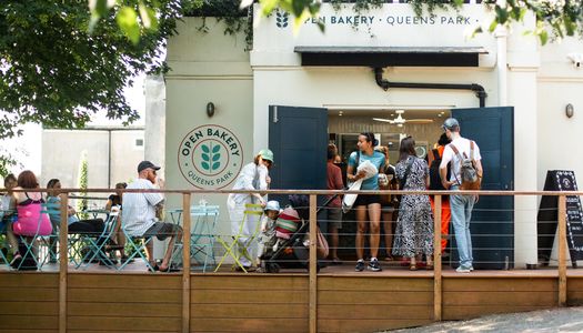 exterior shot of Open Bakery Queens Park. Park dwellers at Queens Park are enjoying pastries, buying bread and coffeee