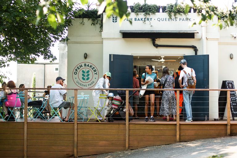 exterior shot of Open Bakery Queens Park. Park dwellers at Queens Park are enjoying pastries, buying bread and coffeee